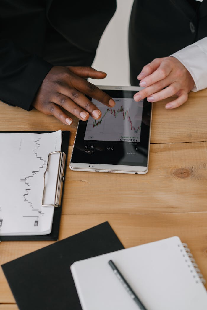 Two business professionals reviewing financial charts on a tablet in an office setting.